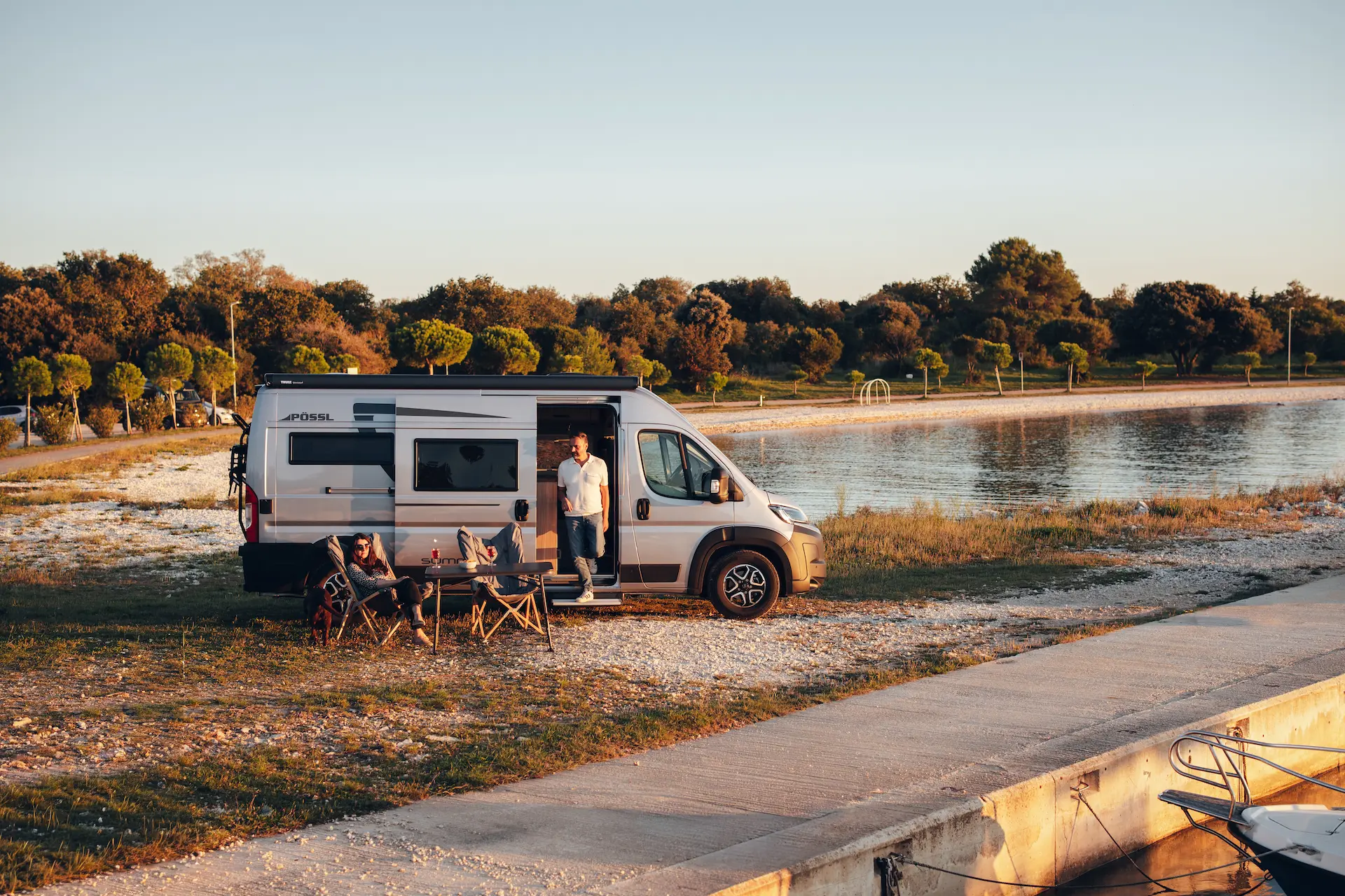 Buscamper aan het meer Originele Pössl camper geparkeerd aan een meer in de natuur
